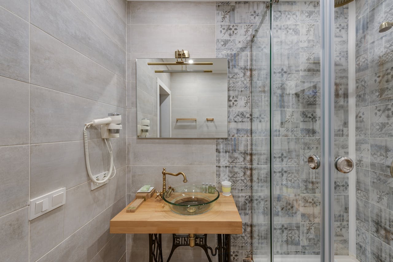 Elegant modern bathroom featuring glass shower, vintage sink, and decorative tiles creating a stylish ambiance.
